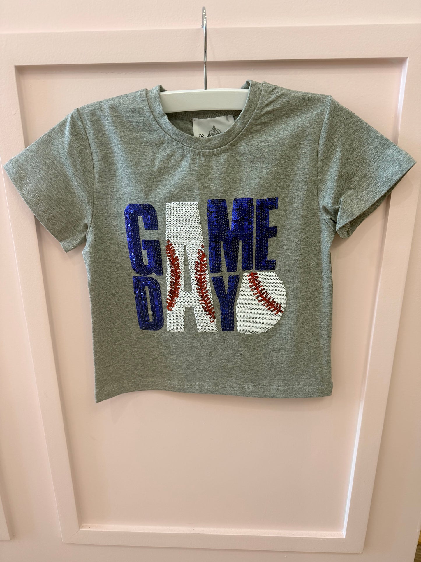 The Belle Cher Baseball Gameday Royal Blue t-shirt features short sleeves and "GAME DAY" in royal blue and white sequins, with red-stitched baseballs forming the letter A—ideal for baseball fans.