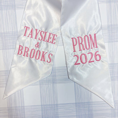 White satin prom sash with 'Tayslee & Brooks' and 'Prom 2026' (Print) text on a checkered background