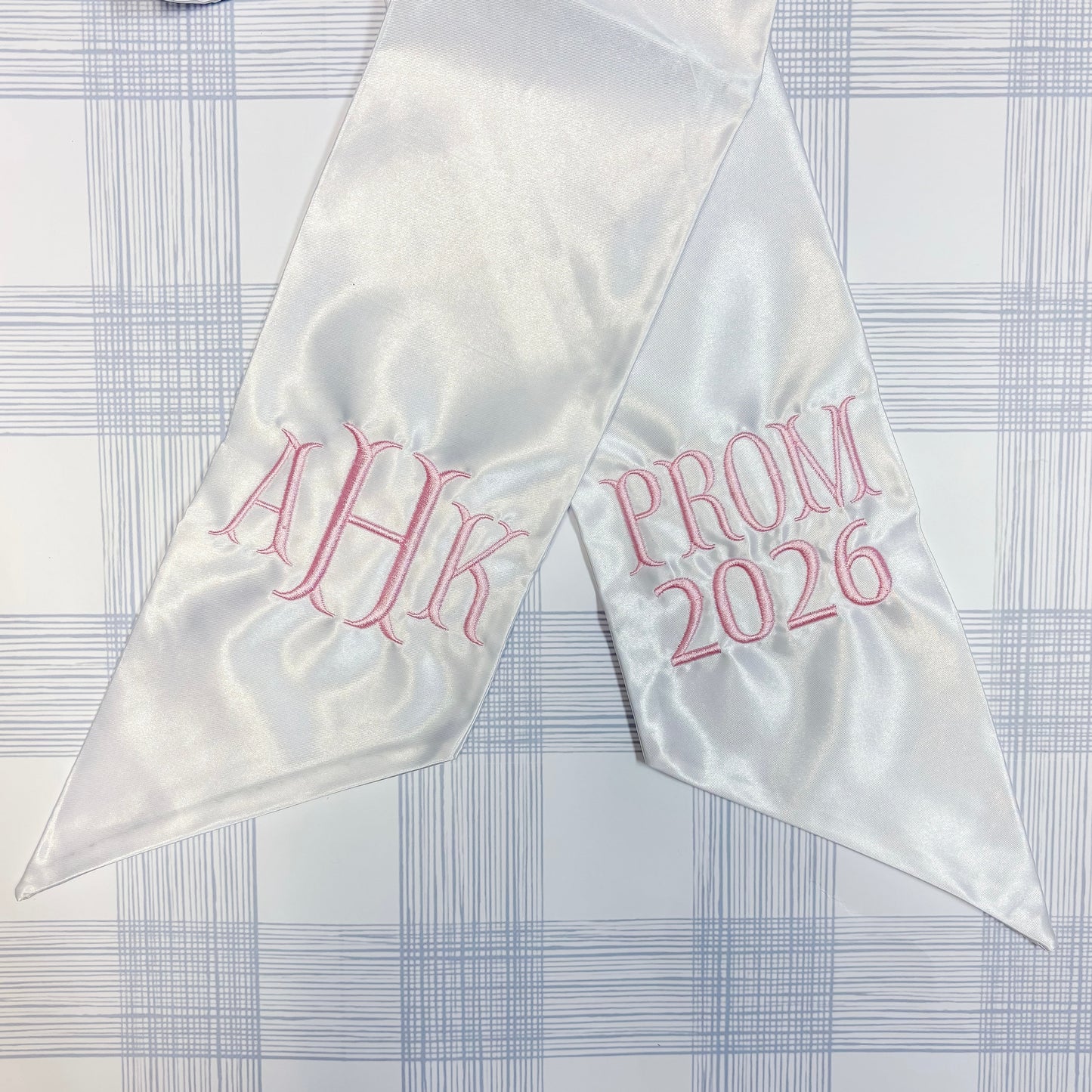 White satin sash with pink Fishtail text on a checkered background