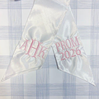 White satin sash with pink Fishtail text on a checkered background