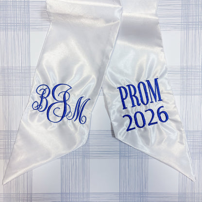 White satin sash with blue Classic monogram  and 'PROM 2026'  text on a checkered background