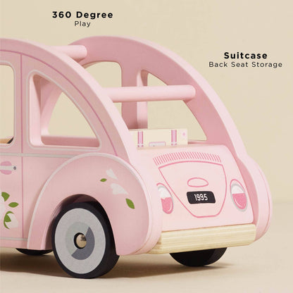The Sophie's Dolls House Toy Car by Le Toy Van, Inc. is a pink wooden car with a floral design and removable suitcase. Enjoy 360-degree play, suitcase back seat storage, retro style, and a fun "1995" license plate—all plastic-free!.