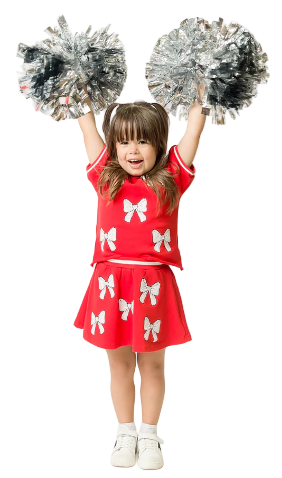 Child in a red outfit with butterfly patterns holding silver pom-poms against a white background