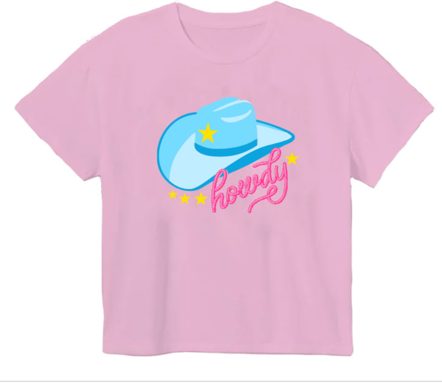 The Azarhia Rodeo Glitter Howdy Hat t-shirt is light pink and features a large blue rodeo hat with a yellow star, the word "howdy" in pink script, and small yellow stars surrounding the design.