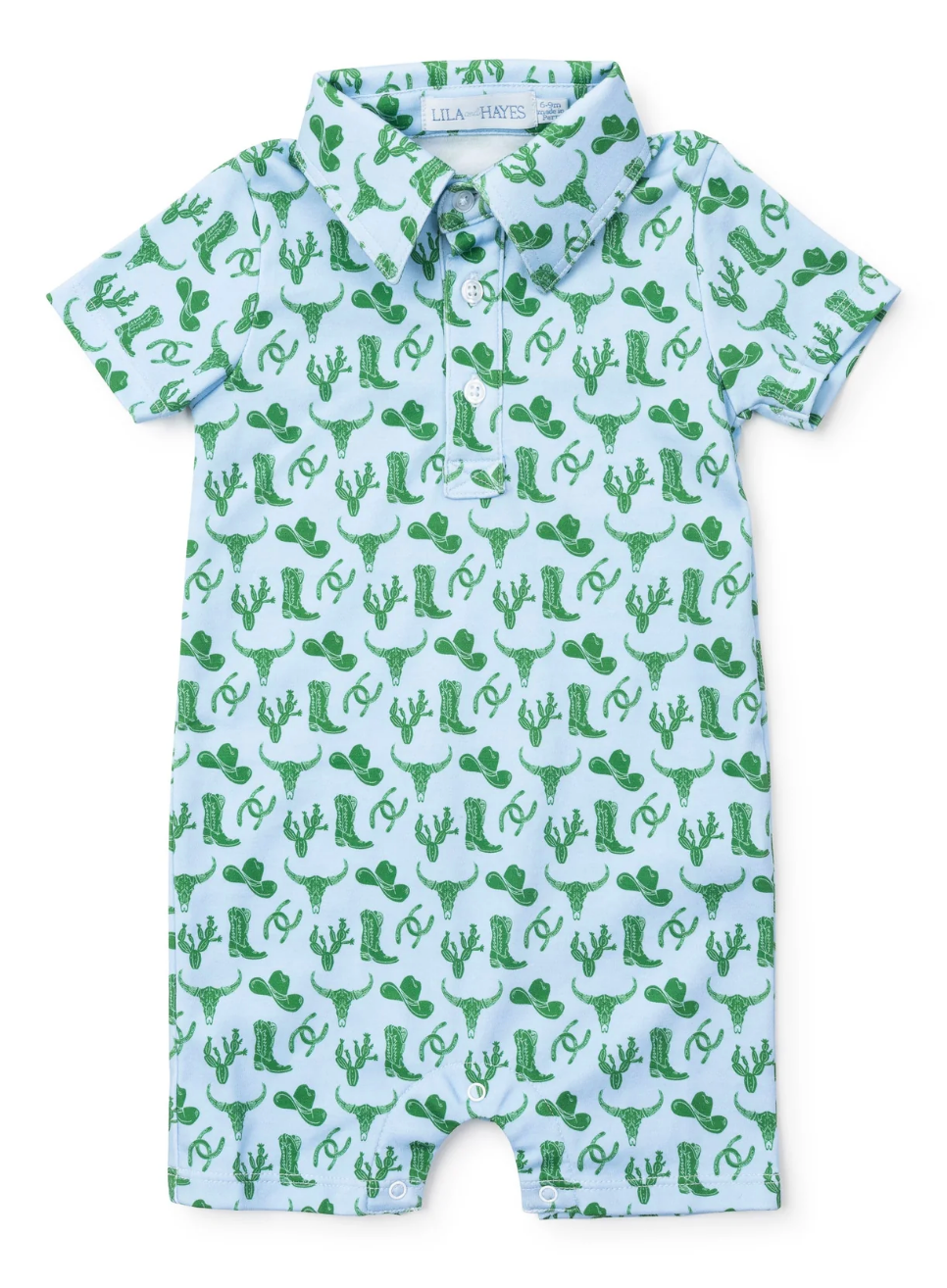 The Lila and Hayes Wildwest Tripp Shortall is a light blue, short-sleeve baby romper with a collar, featuring a green Western-themed print of cowboy hats, boots, cacti, and horseshoes.