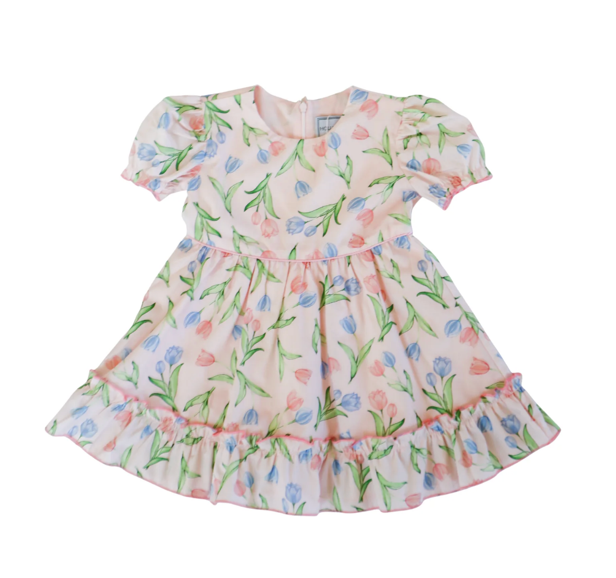 The Hollis Baker Everly Tulips Dress is a light pink, short-sleeved kids' dress with blue and pink tulip prints, green leaves, a round neckline, ruffled hem, and puff sleeves—ideal for spring occasions.