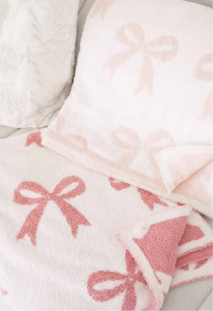 The Caden Lane CuddleLane™ Luxe Blankets | Bows set features a fluffy, soft texture with light and dark pink bow patterns—perfect for nursery décor and adding warmth to any light-colored surface.