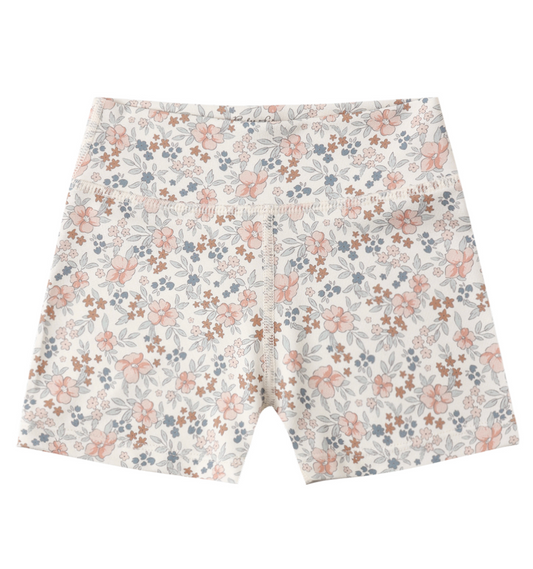 The Rylee & Cru Flower Field Shortie Short features a high-waisted, fitted design with a pink, blue, and brown floral pattern on white and a seamless waistband—perfect for girls' sports or everyday wear.