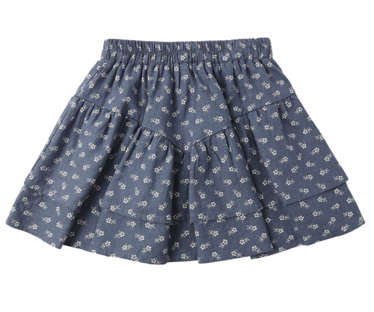 The Rylee & Cru Tiered Mini Ditsy Skirt is a lightweight dusty blue skirt with ruffled tiers, an elastic waistband, and small white floral patterns, shown on a white background.