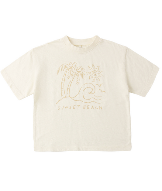 The Sunset Relaxed Tee by Rylee & Cru is a cream-colored cotton t-shirt with a relaxed fit, featuring line art of a palm tree, wave, sun, and birds above the words SUNSET BEACH—ideal for effortless coastal style.