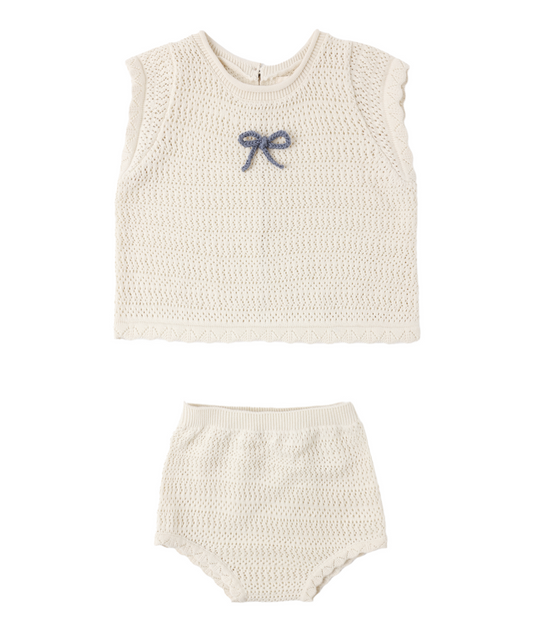 The Scallop Knit Baby Set Natural by Rylee & Cru features a cream-colored knit sleeveless top with scallop cap sleeves, a marine blue bow on the chest, and matching high-waisted bottoms for an adorable look.