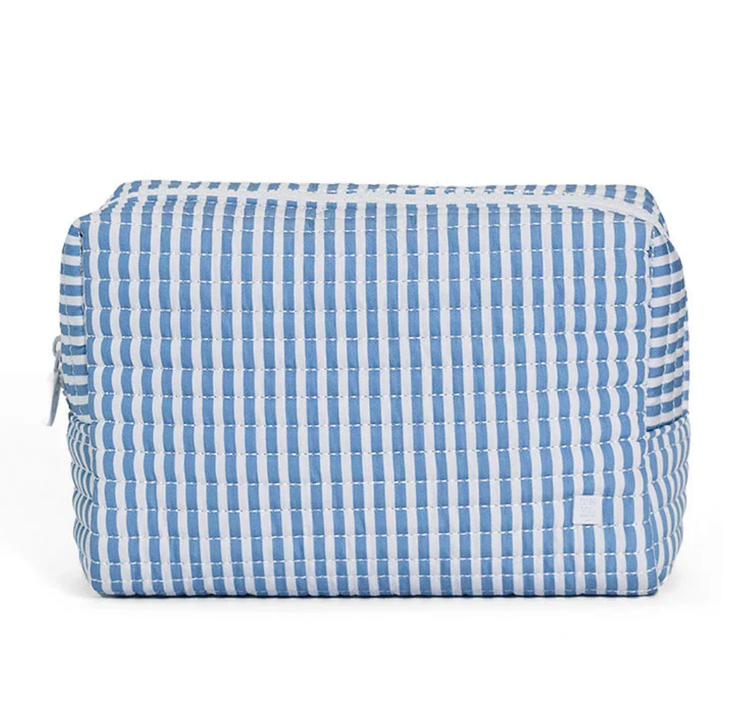 The TRVL QUILTED EVERYDAY BAG by TRVL is a rectangular, quilted travel pouch with blue and white vertical stripes and a top white zipper—perfect for daily use.