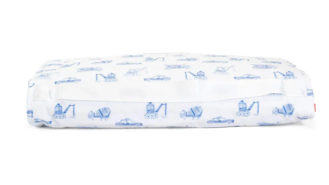 The TRVL Nap Mat by TRVL features a rectangular design with a white, machine-washable cover decorated with blue construction vehicles and cars. The elastic edge ensures a snug fit.