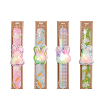 The Mud Pie Easter LED Slapbands by mudpie are bunny-shaped, multi-color light-up bracelets featuring carrots, green gingham, pastel plaid, and flower patterns—perfect as kids’ party favors. Four packaged per set.