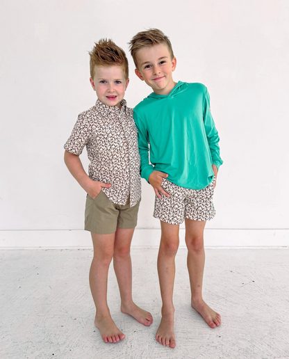 Two young boys wearing matching outfits with floral patterns on a white background