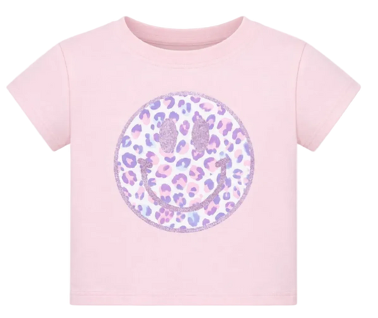 A light pink short-sleeve baby t-shirt featuring a large circular smiley face graphic on the chest. The smiley face is filled with a purple and pink leopard print pattern and outlined with glittery purple details.