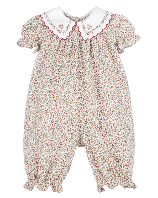 A baby romper with a dense red, green, and yellow floral print on a cream background, featuring a white Peter Pan collar with red embroidered details and scalloped edges.