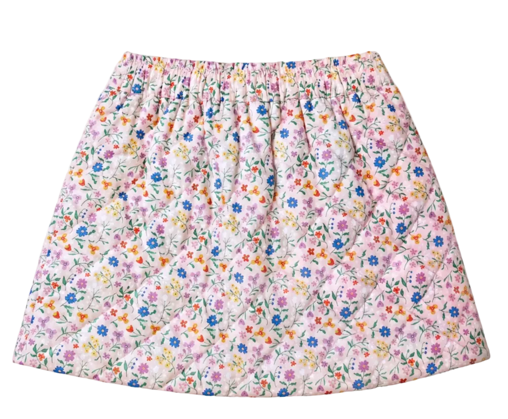 A quilted skirt with a dense, small-scale floral print on a light pink background, featuring blue, purple, orange, and yellow flowers with green stems. The skirt has an elastic waistband and is photographed flat against a solid off-white background.