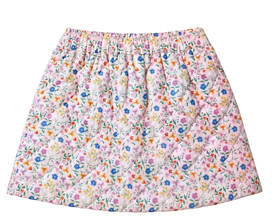 A quilted skirt with a dense, small-scale floral print on a light pink background, featuring blue, purple, orange, and yellow flowers with green stems. The skirt has an elastic waistband and is photographed flat against a solid off-white background.