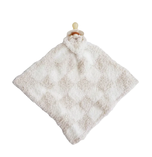A soft, textured baby security blanket in a warm off-white or cream color, featuring a diamond pattern and a pacifier clip with a beige pacifier on a solid white background.