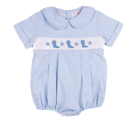 Shop Teeta’s Cowboy Bubble is a light blue baby romper with white smocking, blue bird and star embroidery, a Peter Pan collar, short sleeves, and gently elasticized leg openings for a sweet, classic look.