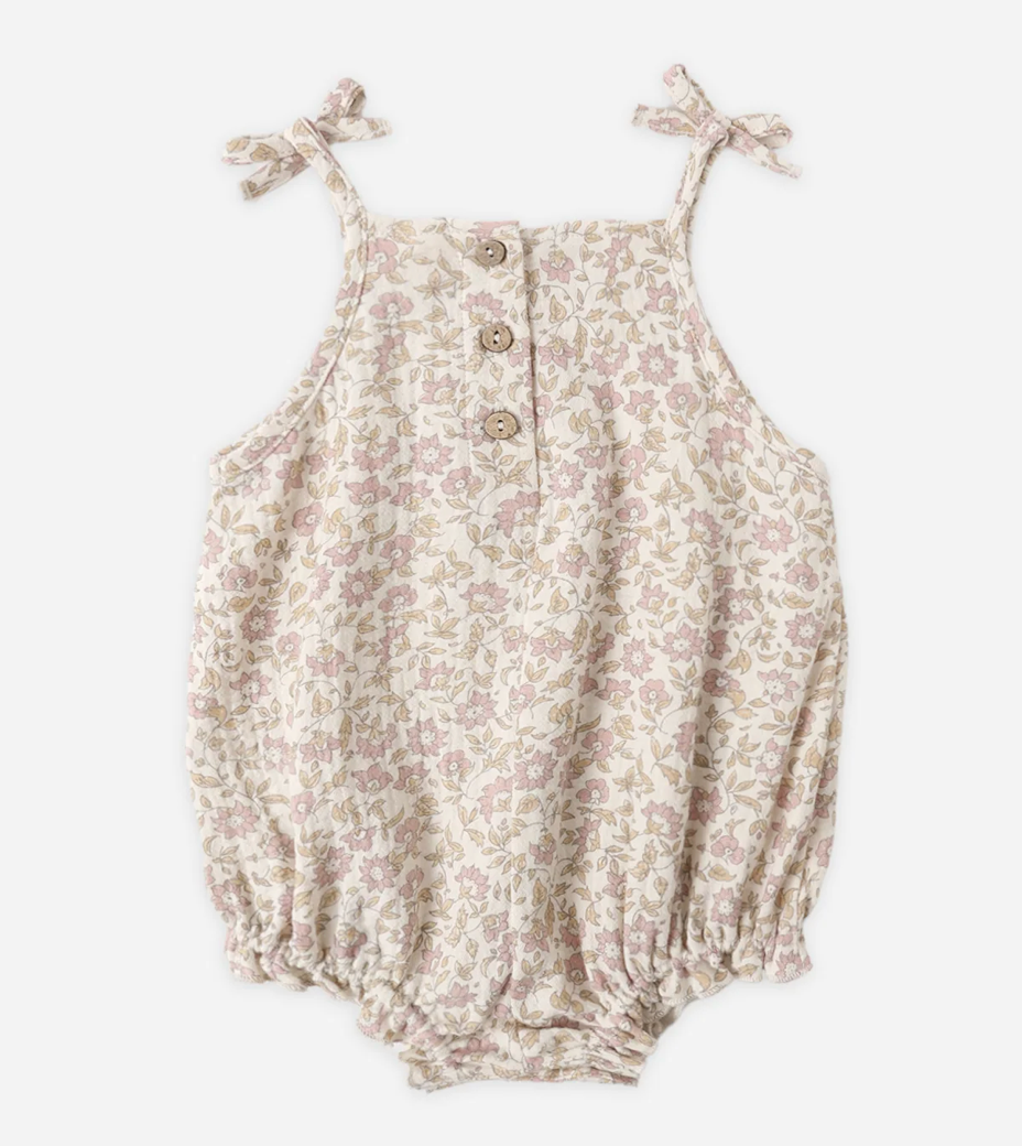 Floral baby romper with tie straps on a white background