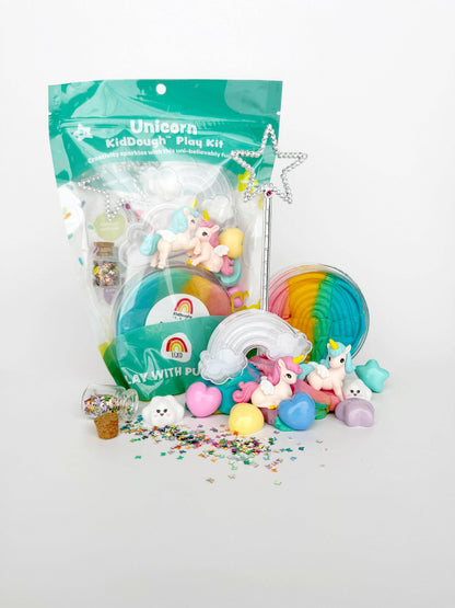 The Earth Grown KidDoughs Unicorn KidDough Play Kit includes toy unicorns, non-toxic rainbow sensory dough, a rainbow with cloud, pastel hearts, star wand, glitter container, and confetti—shown on a white background.